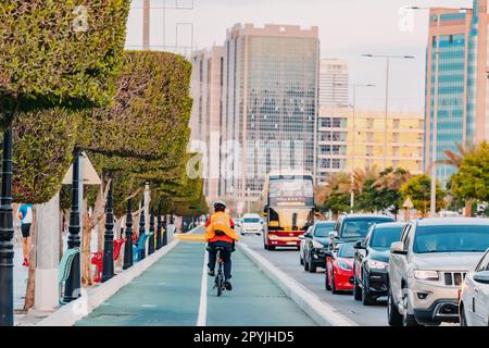 15. Januar 2023, Abu Dhabi, Vereinigte Arabische Emirate: Eine geschäftige urbane Autobahn mit öffentlichen Verkehrsmitteln, Autos und Radweg. Personenverkehr und umweltfreundlicher Fahrradverkehr Stockfoto