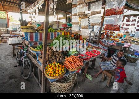 Toliara, Madagaskar - 01. Mai 2019: Obst, Gemüse und Gewürze auf einem typischen afrikanischen Markt, einfache Holzbude, zwei Kinder und Besitzer Stand Stockfoto