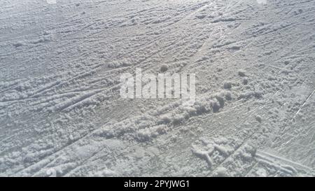 Eis gestreift mit der Spitze der Eisläufer. Eiskunstlauf. Die Oberfläche der Eislaufbahn nach dem Skater-Training. Sonnenlicht auf nassem Quelleis, Schnee und gefrorenem Wasser Stockfoto