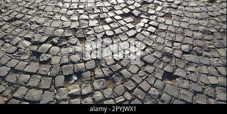 Uralter Bürgersteig. Bürgersteig aus grauen Steinen. Kopfsteinpflaster auf dem Platz der Altstadt. Unebene Fliesen in einem Kreis. Natürliche Steinstruktur. Stockfoto