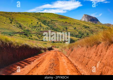 Roter Staub und Schlamm auf der Straße in schlechtem Zustand mit nach Regen gebildeten Kämmen. Die Routen zum Andringitra-Nationalpark sind während der Regenzeit in der Region um Ambalavao, Madagaskar, schlecht Stockfoto