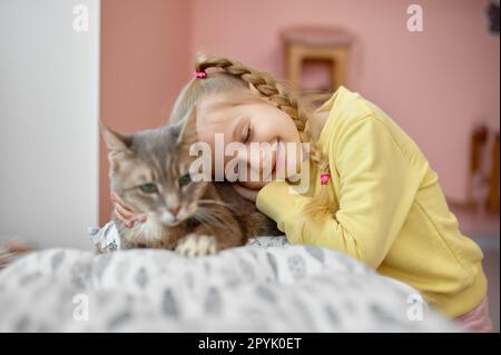 Glückliches lächelndes Mädchen, das flauschige Katze streichelt und Spaß im Tierheim hat Stockfoto