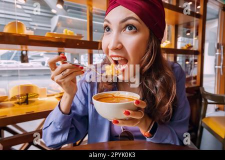 Glückliches Mädchen, das scharfe thai-Suppe Tom Yam in einem authentischen Restaurant isst Stockfoto