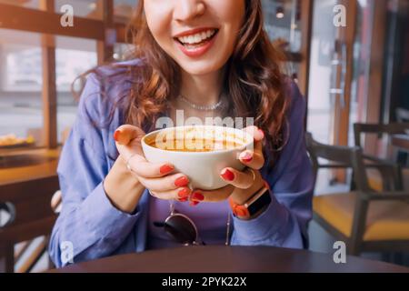 Glückliches Mädchen, das scharfe, heiße, gedämpfte thai-Suppe Tom Yam in einem authentischen Restaurant isst Stockfoto