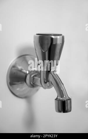 Nahaufnahme eines Wasserhahns an einer weißen Wand. Stockfoto