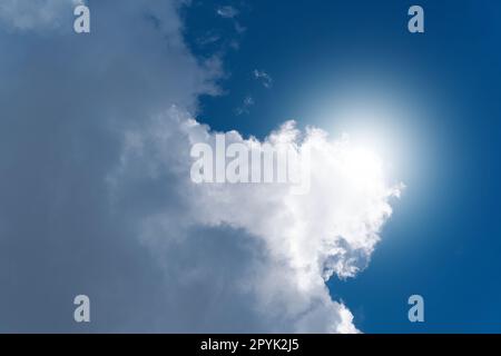 Große weiße Wolke mit der Sonne im Hintergrund an einem Sommertag Stockfoto