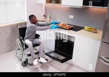 Behinderter Mann, Der Zum Backen Einen Mikrowellenherd Verwendet Stockfoto