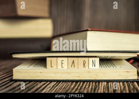 Ein Stapel Bücher, lesen. Stapel Bücher in der farbigen Hülle lagen auf dem Tisch. Offenes Buch mit dem Text Lernen Sie hölzernen Hintergrund, Bildung, Lesen, Lernkonzept Stockfoto