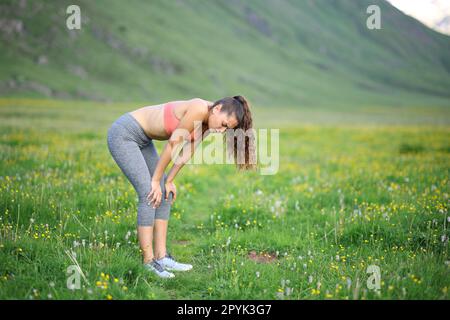 Erschöpfter Läufer in den Bergen ruht sich aus Stockfoto