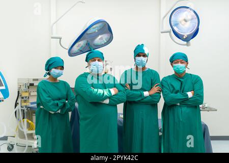 Chirurg und Krankenschwester im grünen Operationskittel stehen sicher mit gefaltetem Arm, bevor sie eine Operation im Operationssaal durchführen. Stockfoto