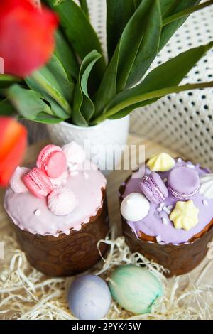 Farbenfrohe Ostereier liegen zusammen mit Ostergebäck mit bunter Schokolade auf einem Holztisch. Osterferien. Stockfoto