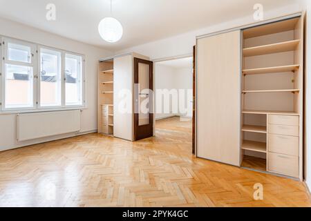 Ein leeres Zimmer in einem Apartment mit Kleiderschrank und Holzparkettboden Stockfoto