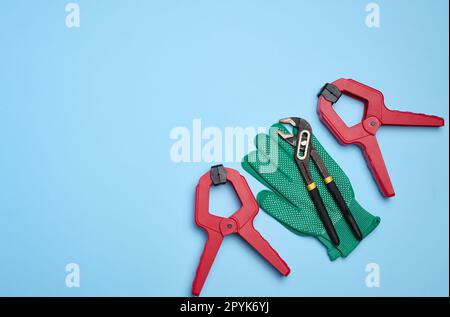 Grüner Handschuh und universeller verstellbarer Schraubenschlüssel aus Metall auf blauem Hintergrund, Draufsicht Stockfoto