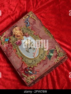 Antikes viktorianisches Buch mit farbenfrohen Edelsteinen. Märchenhaftes Buch mit Skorpion und Fledermaus Stockfoto