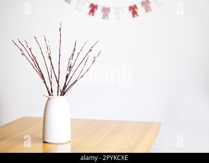 Osterdekoration mit einem Strauß der Weidenäste auf dem braunen Tisch. Stockfoto