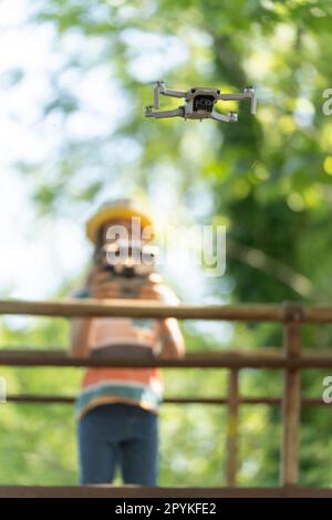 Ein kleines Mädchen fliegt eine kleine Drohne im Park mit einer Fernsteuerung Stockfoto