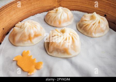 Xiao Long Bao Teigtaschen, frisch gedünstet und auf einer Bambusplatte serviert, für ein malerisches kulinarisches Erlebnis. Stockfoto