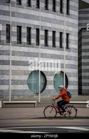 Radfahrer, der an einem BIZ-Gebäude vorbeifährt, das von Mario Botta, Basel, Schweiz, entworfen wurde Stockfoto