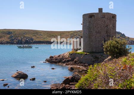 Eine Yacht im New Grimsby Sound segelt vorbei an Cromwell's Castle auf Tresco, mit der Insel Bryher dahinter: Isles of Scilly, Großbritannien Stockfoto