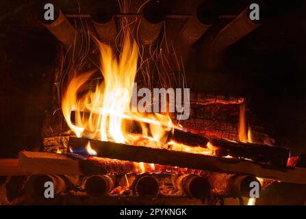 Eine intensive Nahaufnahme eines brennenden Feuers im Kamin, umgeben von feurigen Flammen und der Strahlungswärme des brennenden Holzes. Stockfoto