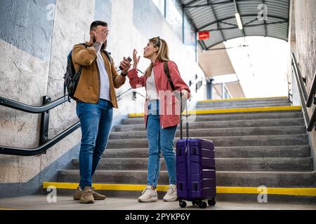 Ein erwachsenes Paar hat die Abfahrt des Zuges verpasst. Die streiten am Bahnhof. Stockfoto