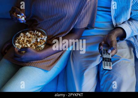 Blick aus einem hohen Winkel auf ein afroamerikanisches Paar, das einen Film mit Popcorn zu Hause sieht Stockfoto