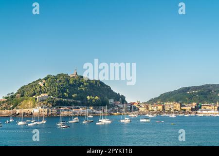 SAN SEBASTIAN, Spanien Juli 08 2022: Blick auf Santa Clara Island. Boote, die mitten in der Bucht von La Concha anlegen. Wunderschönes Reiseziel Stockfoto