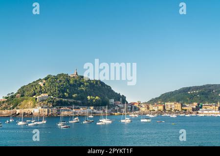 SAN SEBASTIAN, Spanien Juli 08 2022: Blick auf Santa Clara Island. Boote, die mitten in der Bucht von La Concha anlegen. Wunderschönes Reiseziel Stockfoto