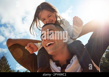 Diese Vater-Tochter-Bindung ist unschlagbar. Ein glücklicher Vater und eine glückliche Tochter, die eine Huckepackfahrt im Freien genießen. Stockfoto