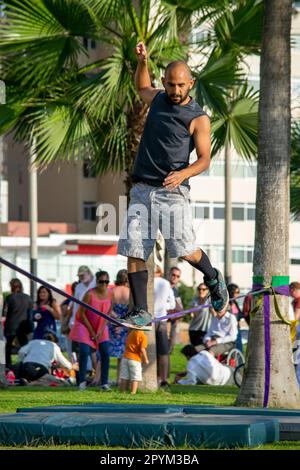 Ein Mann balanciert an einem elastischen Seil in einem Park. Stockfoto