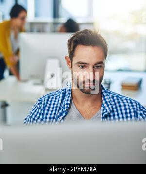 Eine Karriere im Grafikdesign zu verfolgen. Ein Geschäftsmann, der an einem Computer in einem modernen Büro arbeitet. Stockfoto