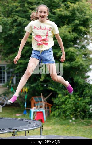 Ein junges Mädchen, das auf einem Trampolin springt, Little Waltham, Essex, England Stockfoto