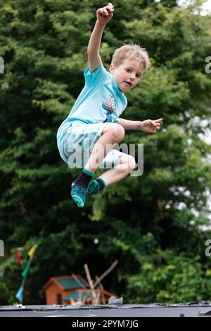 Kleiner Junge, der auf einem Trampolin spielt, Little Waltham, Essex, England. Stockfoto