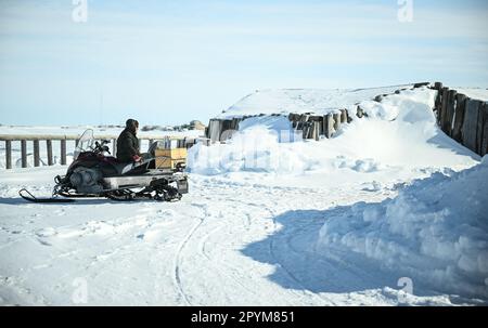 Tuktoyaktuk, Kanada. 27. April 2023. Ein Mann sitzt auf seinem Schneemobil in Tuktoyaktuk in der Arktis. Kredit: Britta Pedersen/dpa/Alamy Live News Stockfoto