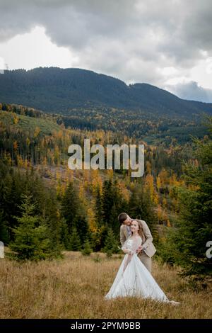 Stilvoller Bräutigam küsst die wunderschöne Braut im Sonnenlicht, perfekter Moment, Bo-ho-Hochzeitspaar. Portrait glücklicher Frischvermählter am Hochzeitstag. Hochzeitspaar Stockfoto