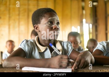 Ondo State, Nigeria - 2. Mai 2023 - Ein Schulmädchen, das seine Klassenarbeit mit Entschlossenheit an der Abereke-Schule in der Flussgemeinde von Ondo State schreibt. Stockfoto