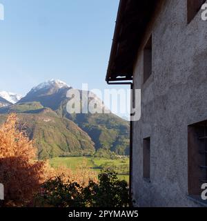 Blick von einem Gebäude neben der Diemoz-Kirche (nicht abgebildet) auf die Felder und schneebedeckten Berge, Aosta Valley, NW Italien Stockfoto