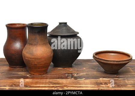 Ukrainisches traditionelles Tonküchengeschirr auf Holztisch. Ländliche Tontöpfe, Kanne und Schüssel. Stockfoto
