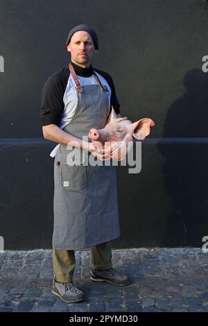 Metzger mit Schürze und Schweinekopf Stockfoto