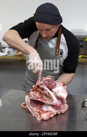 Ein Metzger entbeint einen Schweinekopf Stockfoto