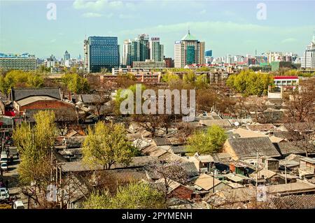 Blick vom Glockenturm auf die alten, dicht gepackten Hutong-Gebäude im Vordergrund und moderne Gebäude im Hintergrund der Skyline von Peking Stockfoto