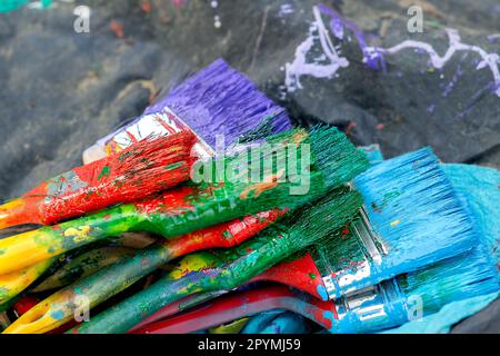 Ein Stapel gebrauchter Pinsel, zum Malen, Pinsel verschiedener Farben, Rot und Gelb, Borsten von Pinseln verschiedener Farben, Grün, Rot, Blau, Violett. Stockfoto