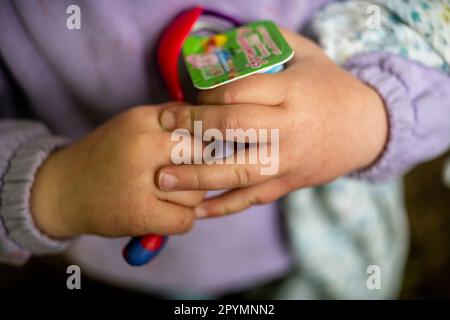 Ein Kleinkind gibt sich mit Joghurt und Löffel die Hände Stockfoto