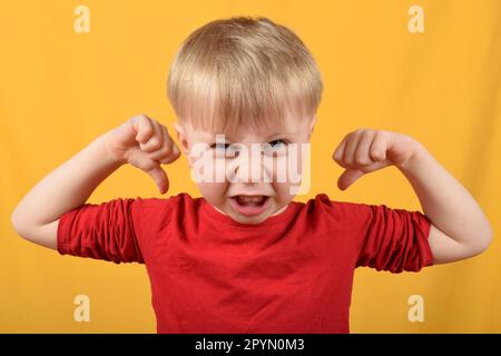 Das lustige Kind zeigt seine Muskeln Stockfoto