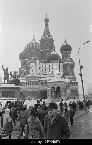 1985: Muscovites gehen vorbei an St. Basilius-Kathedrale und das Denkmal für Minin (stehend) und Pozharsky auf Moskaus rotem Platz im Jahr 1985. Stockfoto