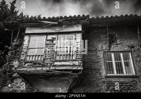 Ein verfallenes Haus im osmanischen Stil in der Altstadt von Antalya Kaleici enthüllt die verblasste Pracht einer vergangenen Ära. Das überhängende Dach und das vorstehende Fenster sind Stockfoto