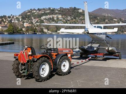 Ein kleiner Traktor, mit dem ein Cessna Skyhawk Wasserflugzeug in die Gewässer des Comer Sees geschoben oder gezogen wird, Como Aero Club, Italien Stockfoto