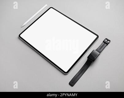 Tablet-PC mit leerem weißem Bildschirm, Smartwatch und Eingabestift auf grauem Papierhintergrund. Platz für Text kopieren. Stockfoto