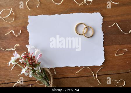 Detail mit zwei goldenen Ringen auf einem rustikalen Holztisch mit Stroh und Sacktuch zur Dekoration und einem isolierten weißen Hintergrund. Vorderansicht. Stockfoto