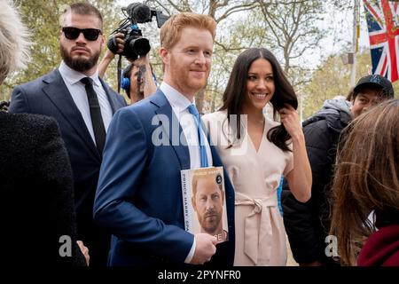 Noch drei Tage vor der Krönung von König Karl III. Am 6. Mai begrüßen zwei Blicke von Harry und Meghan, dem Herzog und der Herzogin von Sussex, am 4. Mai 2023 in der Mall in London, England, die Wohltäter und Fans der Monarchie. Der Harrys Doppelgänger hat eine Kopie des Buches seines wahren Königlichen Mitglieds. Der Herzog wird der Krönung seines Vaters, des Königs, beiwohnen, aber Meghan wird nicht erwartet, anwesend zu sein. Stockfoto